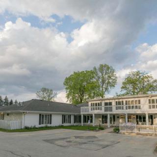 A large two-story building with a cloudy sky in the background and trees surrounding the area.