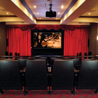 A cozy movie theater with red curtains and rows of seats facing a screen.