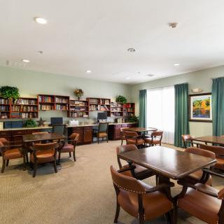 A cozy library with bookshelves, tables, and a computer desk.