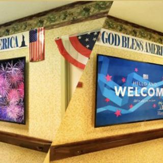 A decorated corner with American flags, patriotic signs, and digital screens displaying a welcome message.
