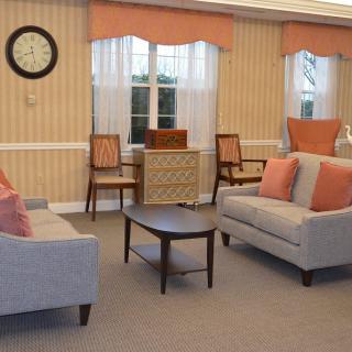 A cozy living room with two sofas, a coffee table, and chairs set against a striped wallpaper backdrop.
