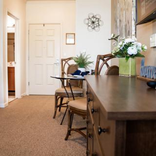 A cozy office interior with a desk and chairs, decorated with plants and artwork.