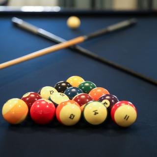 A neatly arranged set of billiard balls with cue sticks on a pool table, ready for a game.