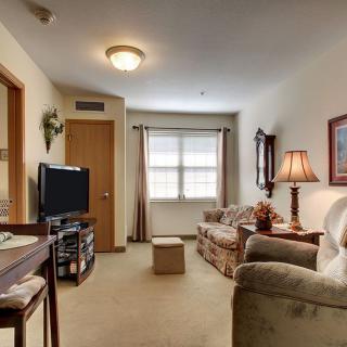 A cozy living room with a sofa, television, and a lamp next to a window.