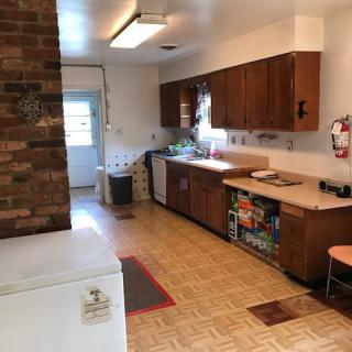 A cozy kitchen with wooden cabinets and a brick feature wall.