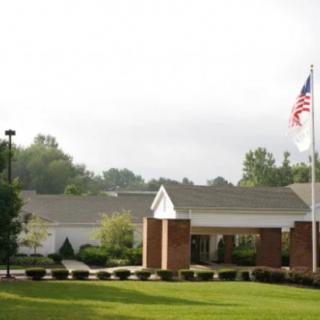 A building with a flagpole and landscaped lawn.