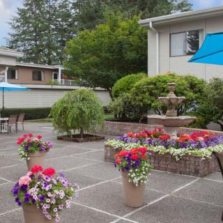 A beautifully landscaped outdoor patio featuring colorful potted flowers and a central fountain.