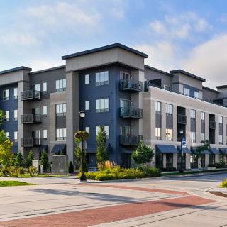 A modern, multi-story apartment building with a stylish exterior and surrounding greenery.