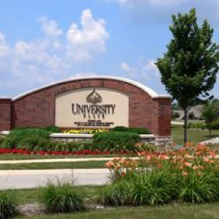 Entrance sign to University Park surrounded by well-maintained gardens and trees.