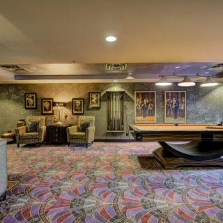A cozy recreation room with seating and a pool table, decorated with artwork and soft lighting.
