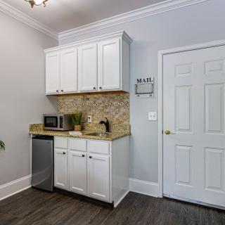 A small modern kitchen corner with white cabinets, a countertop, and appliances including a mini fridge and microwave.