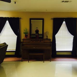 A cozy living room featuring a piano, decorative curtains, and a mirror.