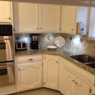A modern kitchen with white cabinets, granite countertops, and stainless steel appliances.