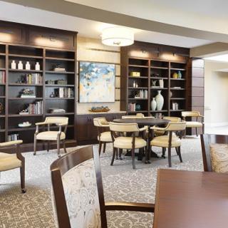 A modern library space with bookshelves, tables, and chairs.