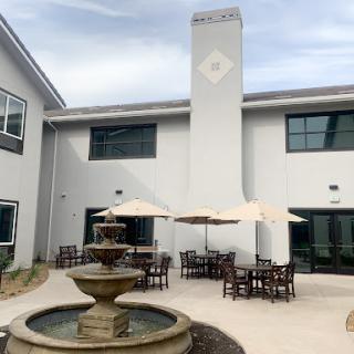 A serene outdoor courtyard featuring a fountain and comfortable seating with umbrellas.