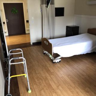 An empty hospital room with a bed and a walker beside it.