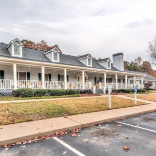 A suburban house with a spacious front porch and adjacent parking lot.