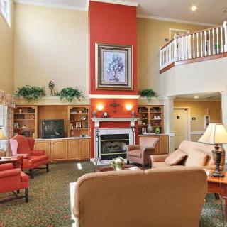 A cozy living room with a central fireplace, comfortable seating, and decorative bookshelves.