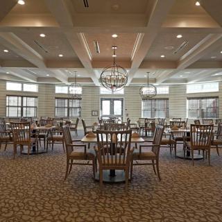 A spacious dining room with neatly arranged tables and chairs under a large chandelier.