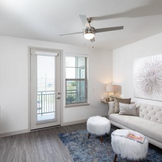 A modern and minimalist living room with a comfortable sofa, stylish artwork, and a ceiling fan.