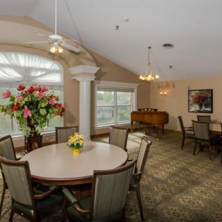 A well-lit dining area with tables and chairs, decorated with vibrant flowers.