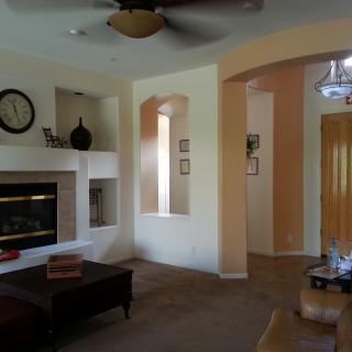 A cozy living room featuring a fireplace, a coffee table, decorative items, and a ceiling fan.