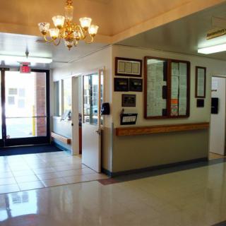 A well-lit lobby with a chandelier, featuring an entrance and a reception area.