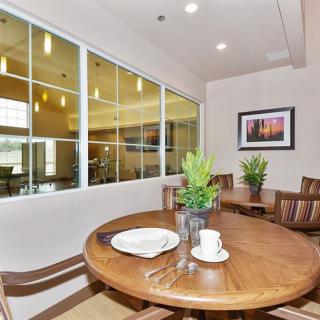 A cozy dining area with a wooden table and chairs, adorned with plants and art on the wall.