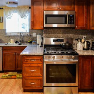A modern kitchen with wooden cabinets, featuring a stainless steel oven and microwave.