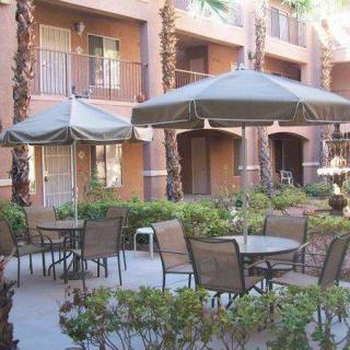 An outdoor patio area with tables, chairs, and umbrellas in an apartment complex courtyard.