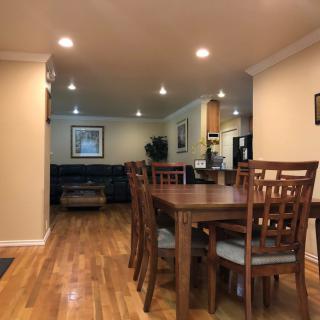 A spacious open-plan living and dining area with hardwood floors, featuring a large wooden dining table and chairs.