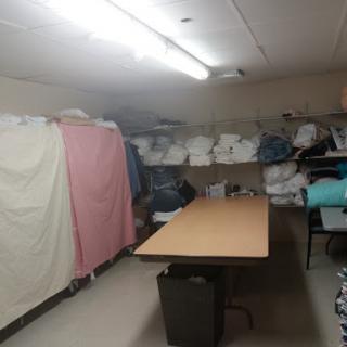 A functional laundry storage room equipped with a table and neatly stacked linens.