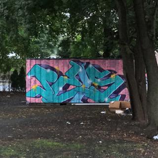 A vibrant mural featuring bold colors, set against a backdrop of trees.