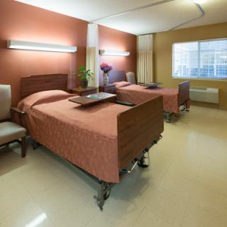 A well-lit hospital room featuring two beds, designed for patient comfort.
