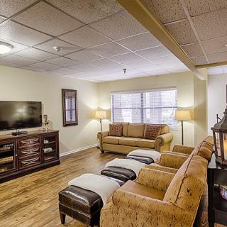 A cozy living room featuring comfortable sofas, a television on a wooden stand, and warm lighting from lamps.