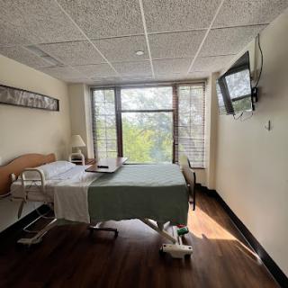 A well-lit hospital patient room with a bed, window view, and a television.