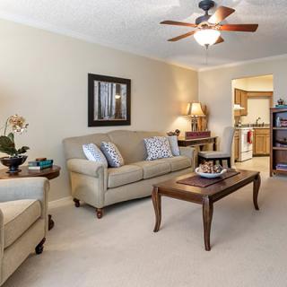 A cozy living room with a sofa, coffee table, and ceiling fan.