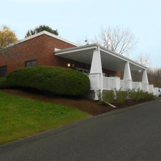 A modern brick building with landscaped greenery and a distinctive roof structure.
