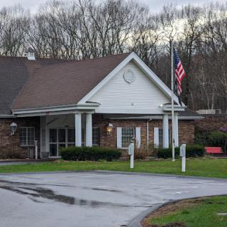A welcoming building featuring a flag in front, set against a natural backdrop.