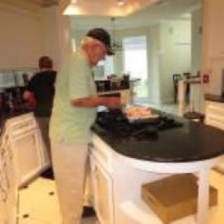 An elderly person cooking in a modern kitchen.
