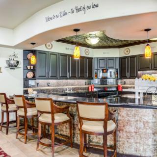 Stylish kitchen with a bar area featuring dark cabinets, granite countertops, and pendant lighting.
