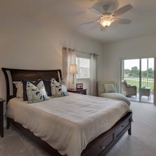 A beautifully designed bedroom featuring a king-size bed, stylish pillows, and a serene view through the sliding glass doors.