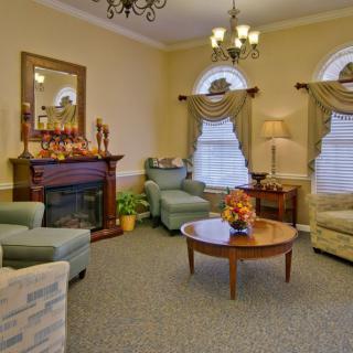 A cozy living room with elegant furnishings, featuring a fireplace and chandelier.