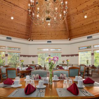 An elegant dining room with beautifully set tables and a grand chandelier overhead.