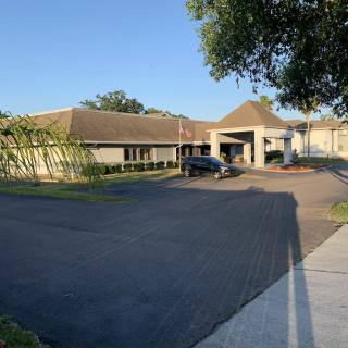 A building with an entrance surrounded by a driveway and trees under clear blue sky.