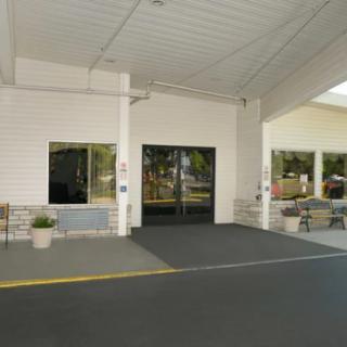 Entrance of a building with an awning and glass doors, featuring outdoor benches.