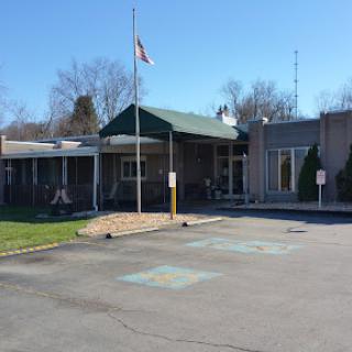 A view of a facility with a green roof and an American flag in front.