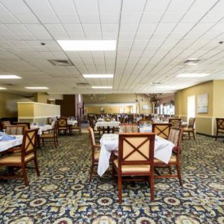 An empty restaurant dining area with neatly arranged tables and chairs on a carpeted floor.