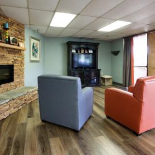A cozy living room with modern decor, featuring colorful chairs and a stone fireplace.