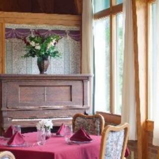 A cozy restaurant interior with a table set for dining, featuring a decorative vase with flowers near large windows.